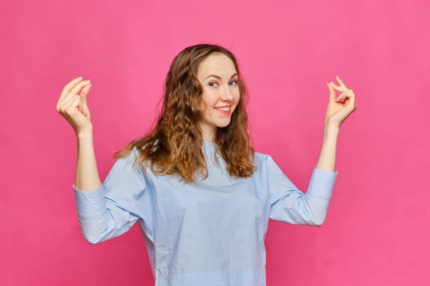 Stylish caucasian girl in a pale blue t-shirt shows a gesture of snapping fingers on a pink background. Stylish caucasian girl in a pale blue t-shirt shows a gesture of snapping fingers on a pink background. Close up. click finger stock pictures, royalty-free photos & images
