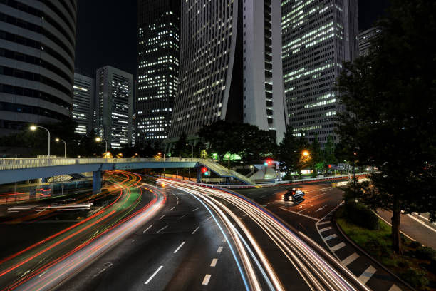 istock Traffic light trails on highway intersection amidst skyscraper buildings at night in Tokyo, Japan 1213335541
