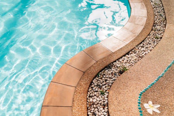 istock Curved swimming pool paved edge with pebbles. Clean transparent pool water waves background. 1213336713