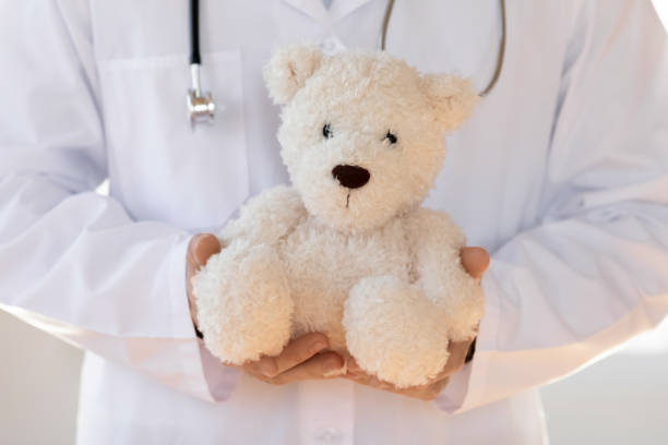 istock Young pediatrician in white coat holding toy in hands. 1213336918