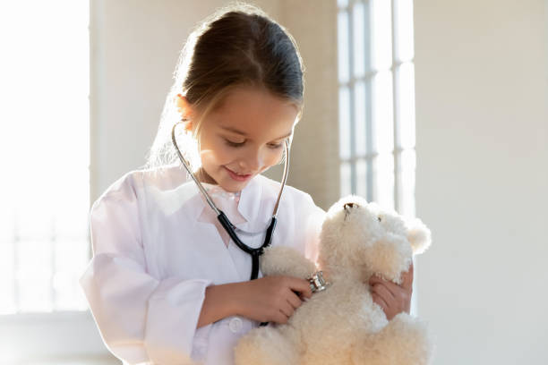 istock Smiling adorable small girl wearing white coat, using stethoscope. 1213336925