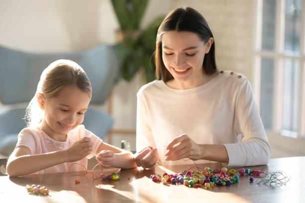 istock Smiling young mom stringing beads on needles with little daughter. 1213336944