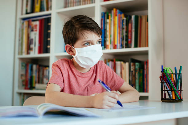 istock Child wearing face mask self-studying at home during coronavirus outbreak. 1213342919