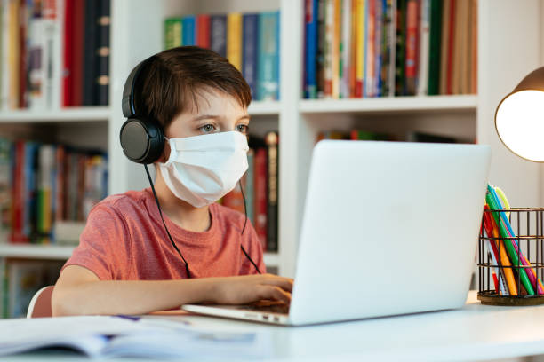 Child wearing face mask learning at home. stock photo