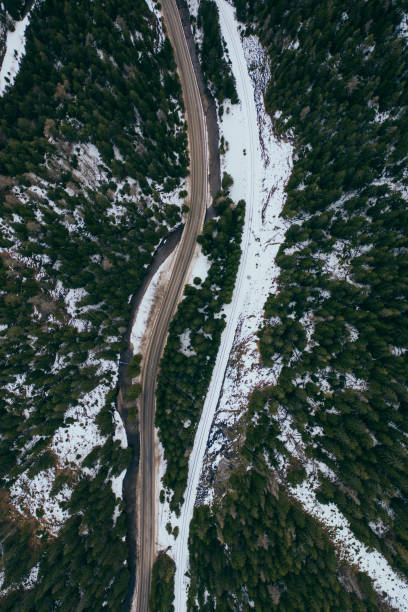 road in snow covered forest, top down aerial view