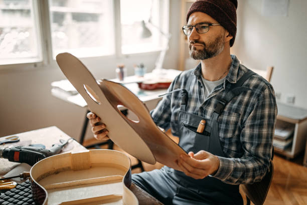 istock Man working on a model of new acoustic guitar in workshop 1213348799