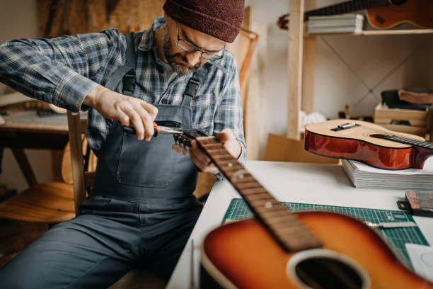 istock Craftsperson fixing acoustic guitar in his home workshop 1213348804