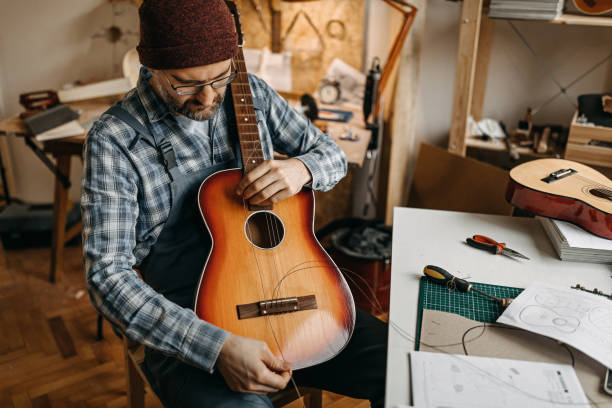 istock Repairman setting up strings on acoustic guitar in workshop 1213349172