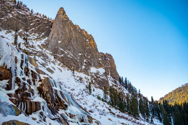 A frozen waterfall, a tall mountain peak, and the pine trees of California's Sequoia National Park all come together in this wild nature scene. A clear blue sky, and no people to be seen. Truly secluded.