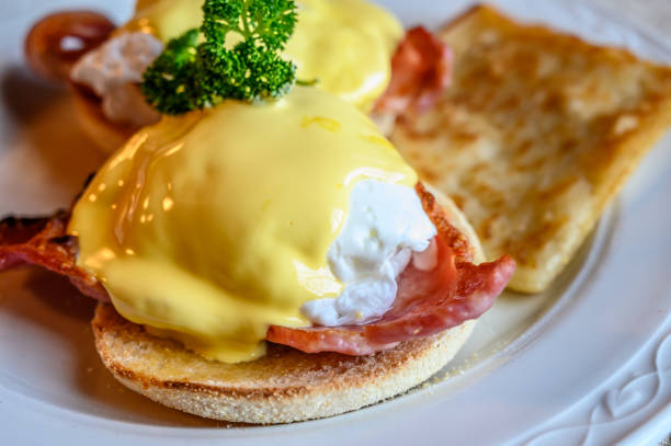 istock Weekend brunch in Scotland with two eggs benedict on homemade muffuns with roasted bacon and yellow hollandaise sauce. 1213351570