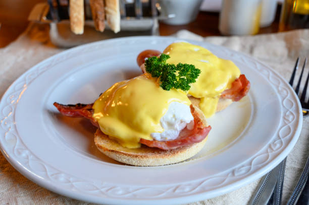 istock Weekend brunch in Scotland with two eggs benedict on homemade muffuns with roasted bacon and yellow hollandaise sauce. 1213351634