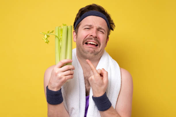 man holding celery crying. I hate vegetables but should eat for healthy diet. Funny handsome sporty man with mustache holding fresh celery crying. I hate vegetables but should eat for healthy diet. Studio shot on yellow wall eating body building muscular build vegetable stock pictures, royalty-free photos & images