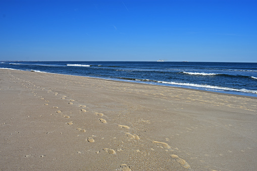Light winds off the ocean cause waves to crash into the shore at a Sandy Hook, New Jersey, beach