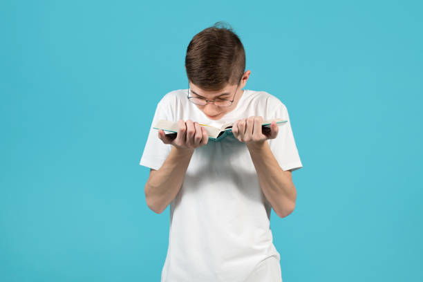 istock a nerd with glasses reading a book, holding it too close in front of him 1213374965