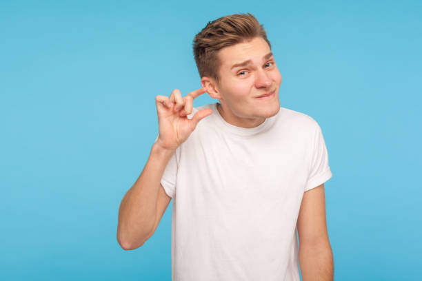 trop petit ! verticale de l’homme drôle dans le t-shirt blanc faisant un peu de geste avec des doigts et le sourire sarcastique - less fortunate photos et images de collection