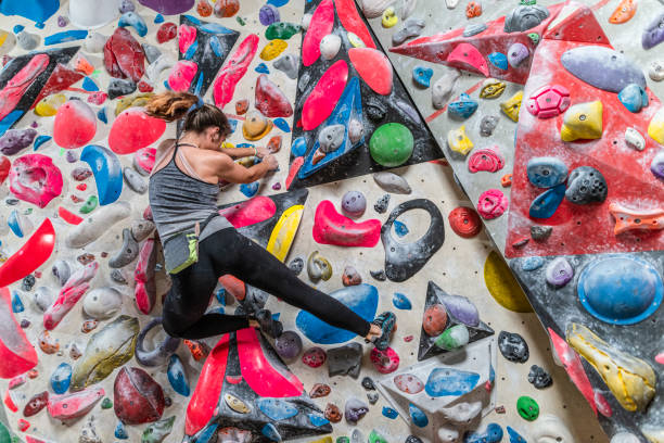 mulher escalando parede de escalada - climbing wall rock climbing holding reaching - fotografias e filmes do acervo