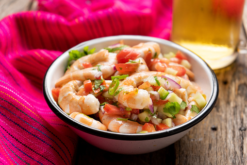 Traditional mexican shrimp ceviche with tomato and serrano pepper on wooden background