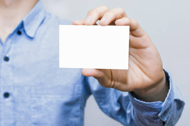 istock Man holding white business card on concrete wall background. 1213407903