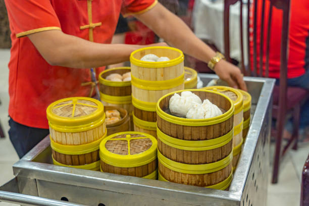 Waitress in Chinese costume serving dimsum in bamboo steamer boxes stock photo