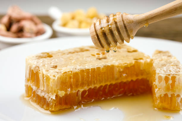 Honeycomb dipper and honey close up on white background