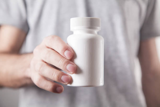 istock Man showing white bottle of pills. 1213426563