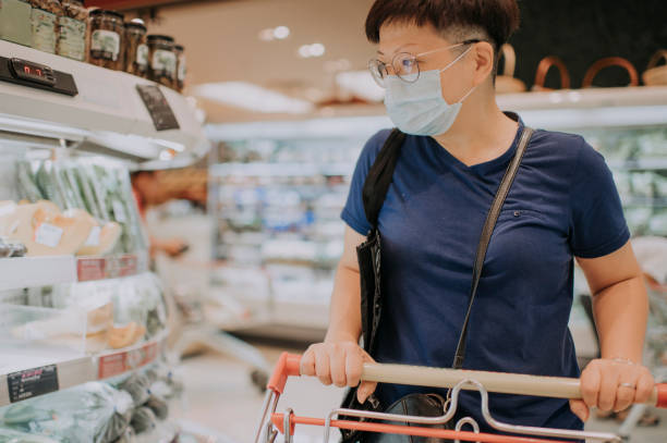 une femelle chinoise asiatique portant un masque sortant faisant des emplettes dans le supermarché achetant des légumes - shopping mall shopping sale retail photos et images de collection