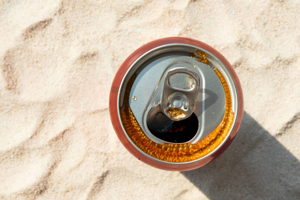 Cola on sand background. Summer soda drink in aluminum can. Refreshment on beach, top view
