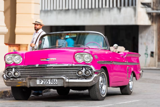 ハバナシティキューバから旧市街で彼のアメリカのピンク1958シボレークラシックカーコンバーチブルにキューバの男 - セリエキューバレポート - cuba car chevrolet havana ストックフォトと画像