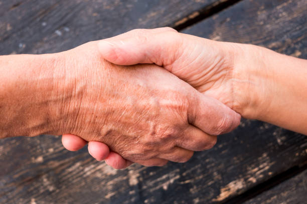 Black and white hands clasped against a background of office blinds.