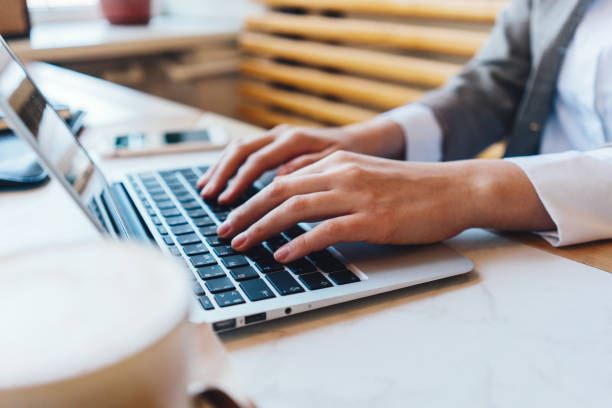 istock Woman's hands on laptop keyboard texting and typing new ideas and message. Table with cup of coffee in cafe. Close-up 1213433686
