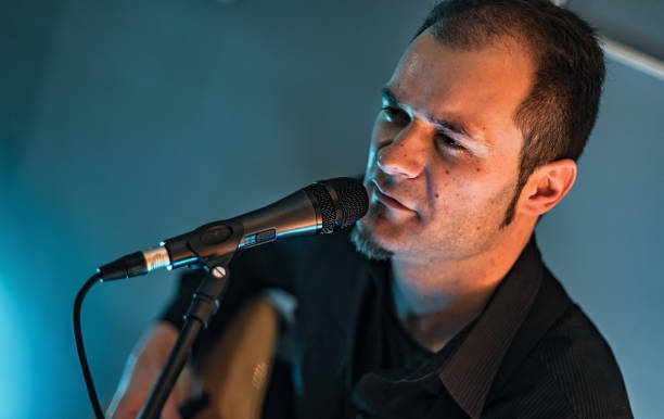 istock Man playing acoustic guitar and singing on stage 1213437197