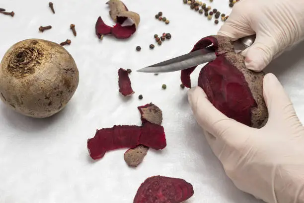 Photo of Hands in gloves peel beets. Healthy winter foods. White background.