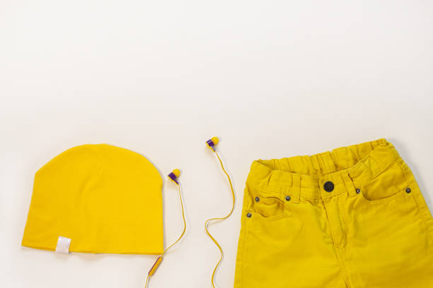 istock Yellow flatlay jeans, cotton hat and headphones on white background copy space,top view.Spring summer fashion clothing 1213442701
