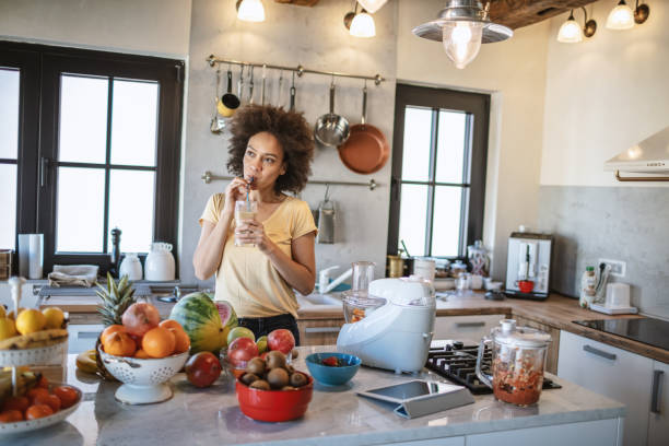 istock African woman drinks a fresh smoothie in the kitchen 1213443372