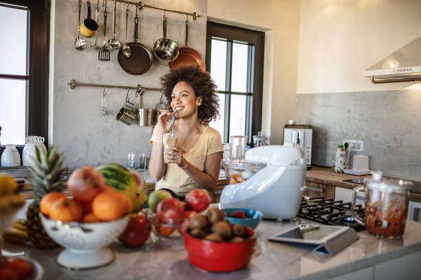 istock African woman drinks a fresh smoothie in the kitchen 1213443417