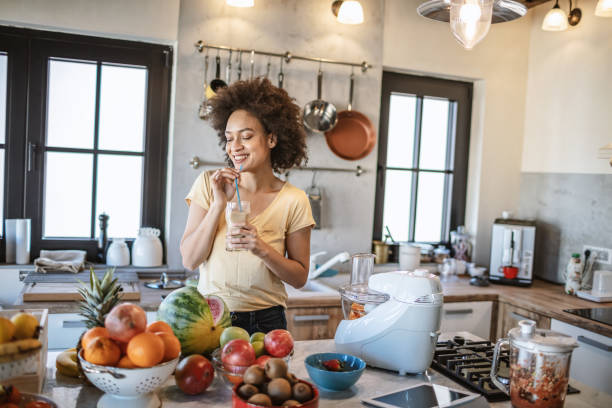 istock African woman drinks a fresh smoothie in the kitchen 1213443575