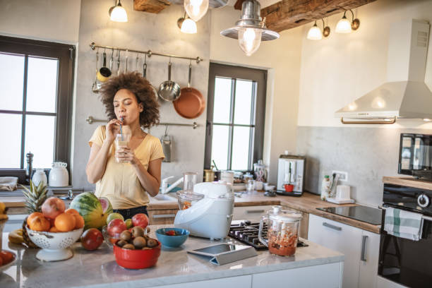 istock African woman drinks a fresh smoothie in the kitchen 1213443674
