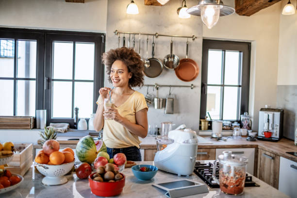 istock African woman drinks a fresh smoothie in the kitchen 1213443850