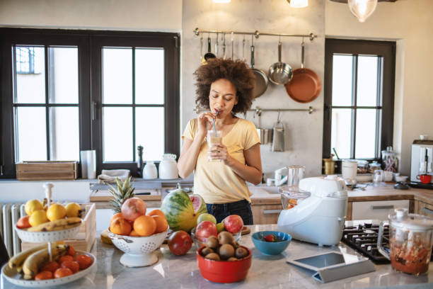 istock African woman drinks a fresh smoothie in the kitchen 1213444035
