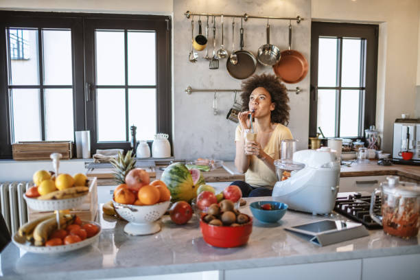 istock African woman drinks a fresh smoothie in the kitchen 1213444145