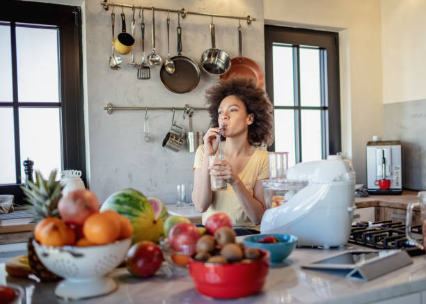 istock African woman drinks a fresh smoothie in the kitchen 1213444218