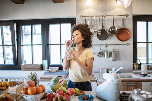 istock African woman drinks a fresh smoothie in the kitchen 1213444317