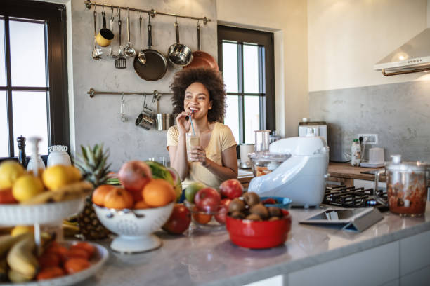 istock African woman drinks a fresh smoothie in the kitchen 1213444468