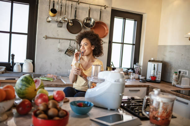 istock African woman drinks a fresh smoothie in the kitchen 1213445065