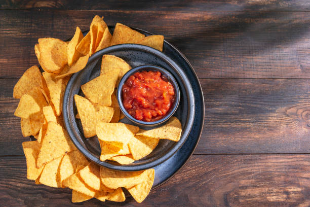 istock Nachos corn chips with salsa dip sauce on blue plate, rustic wooden background. Top view, flat lay with copy space. 1213445091