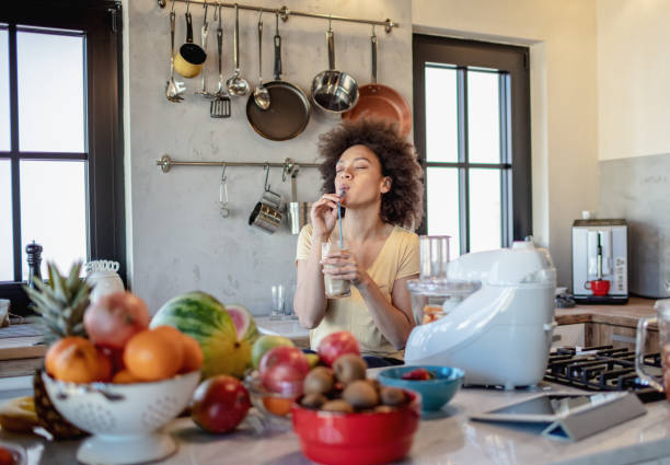 istock African woman drinks a fresh smoothie in the kitchen 1213445127