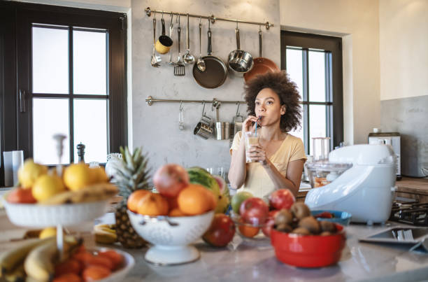 istock African woman drinks a fresh smoothie in the kitchen 1213445182