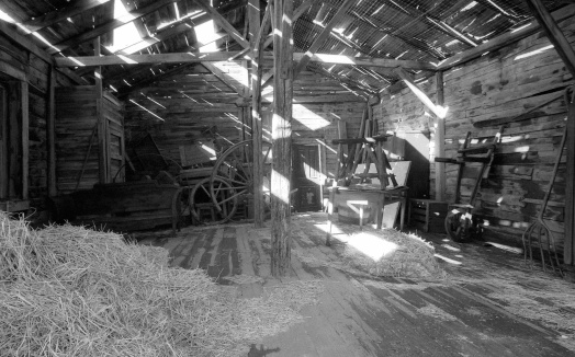 Old barn interior with flashing lights through leaky roof. Black and white picture.
