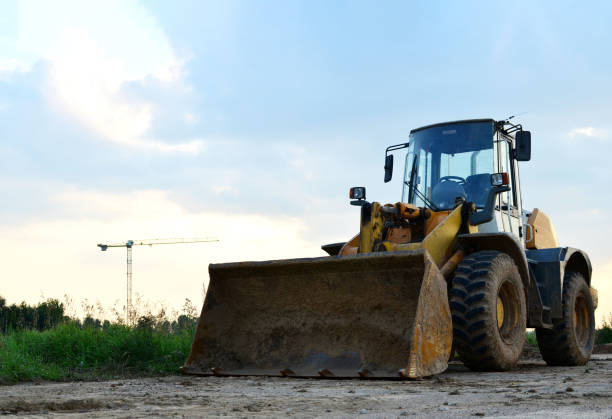 istock Front-end loader working on construction site during the renovation of the road. Laying or replacement of underground storm sewer pipes. Installation of water main, sanitary sewer, storm drain systems 1213451071