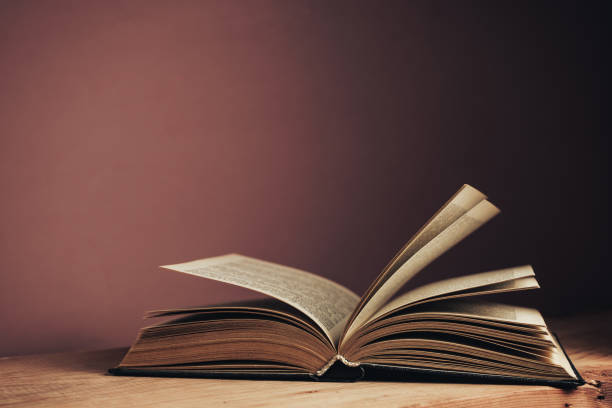 istock Beautiful open vintage ancient book. Pattern background for design. The book on a red wooden table and red wall background. 1213451404